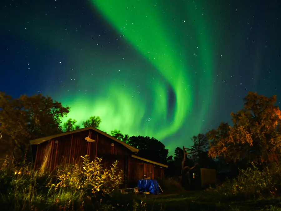 Aurora boreal sobre uma cabana na Lapônia sueca